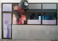 Sala com porta contendo adesivação de uma mulher nas tolidades lilás claro e escuro; na janela também há adesivo com perfis femininos nas de várias etnias