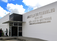 Fachada da edificação nas cores branca e preta. Letras na cor prata.