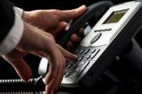 Telefone preto com uma mão de um homem teclando