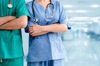 Homem de bata de hospital verde e mulher de bata de hospital azul ambos em um corredor de hospital
