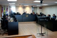 Foto da audiência com o desembargador João Leite a centro e advogados ao lado esquerdo e direito
