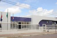 Prédio branco com detalhes azuis, 3 bandeiras à esquerda