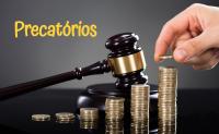 Foto de um martelo preto e pilhas de moedas douradas