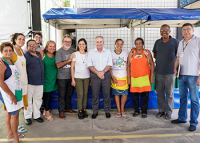 Vários homens e mulheres de etinias diversas pousando para foto em frente a barracas de feira 