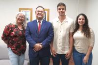 Foto com quatro pessoas em pé, sendo duas mulheres nas extremidades e dois homens no meio.