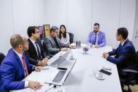 Foto de reunião com muitas pessoas sentadas em torno de uma mesa.