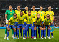 Jogadoras de camisa amarela e short azul em um campo de futebol