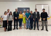 Grupo de cinco mulheres e cinco homens em pé em frente a uma lousa em uma sala de aula