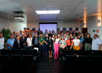 Grupo de pessoas vestidas com roupas de diversas cores reunidas para uma fotografia. 