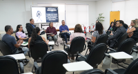 Vários homens e mulheres reunidos  sentados em círculo