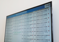 Tela de televisão com lista de horário com números de processos e nomes das partes
