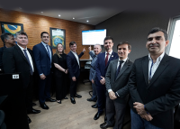 Usanto ternos escutos, dirigentes da OAB, TRT e MPT posam mostrando ao fundo um monitor que exibe a pauta de audiências em tempo real