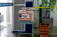Caixa de madeira sobre mesa azul repleta de licros doados para campanha de incentivo ao hábito da leitura.