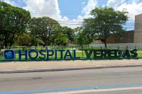 Fachada de uma unidade hospitalar. Há grades e várias árvores.Há, ainda letras grandes e a logo do estabelecimento de serviços de sáude.