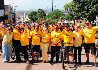 Varias pessoas, de frente, com camisas amarelas alusivas ao setembro amarelo, com as mãos direitas e esquerdas levantadas