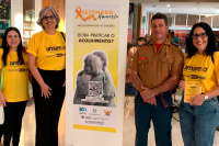 Três mulheres vestidas com camiseta amarela e um militar com a farda do Corpo de Bombeiros. Há um cartaz, com ilustração da campanha setembro amarelo