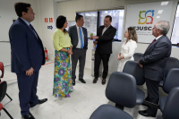 Grupo de pessoas de pé conversa, tendo ao fundo placa com o nome CEJUSC