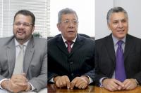 Três homens de paletó e gravata e óculos de grau, sendo um branco e dois morenos, todos de cabelo branco