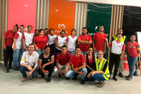 Várias pessoas vestidas de camisas vermelhas e também brancas. Elas estão reunidas para uma foto. Umas estão de pé e outras agachadas. 