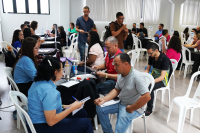 Homens e mulheres sentados e também em pé aguradando a vez de serem atendidos.