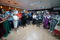 Vários homens e mulheres reunidos de pé em um círculo. Todos estão aplaudindo.