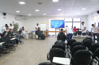 Sala com alguns homens cortando cabelo de outros homens