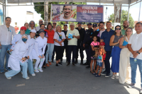 Grupo de pessoas embaixo de uma tenda com uma faixa escrito "prevenção vai à feira" 