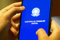 Mãos brncas segurando carteira de trabnalho azul com brasão da Repúlblica.Nela está escrita Carteira de Trabalho Digital.