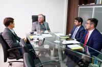 Quatro homens de terno sentados à mesa de reunião, com olhar sério, tendo na ponta o presidente do TRT da 19ª Região, desembargador Marcelo Vieira