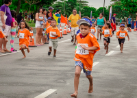 Crianças vestidas de camisetas na cor laranja. Elas participam de uma corrida de rua em prol do combate ao trabalho infantil.