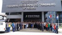 Grupo de pessoas posa de mãos dadas em frente ao TRT-19