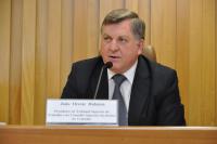 Ministro Dalazen sentado em uma bancada usando paletó preto, blusa branca e gravata cinza escura