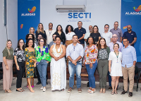 Várias pessoas reunidas para uma foto. Destrás delas há um banner branco e azul. 