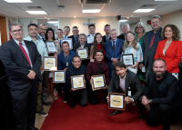 grupo de homens e mulheres com trajes formais segurando uma placa de certificado
