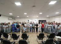 Grupo de pessoas em pé em um auditório, em frente a um telão