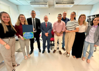 Grupo de pessoas em pé em um semi círculo, com uma das mulheres com um certificado na mão