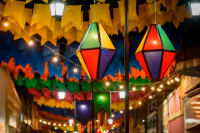 Luzes, bandeirinhas coloridas e dois balões coloridos enfeitando a rua no Dia de São João