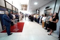 Várias pessoas reunidas escutam homem de terno escuro discursar.