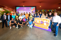 Grupo de pessoas vestidas com roupas de exercício, todos sorrindo, próximos de um tórem com a inscrição TRT AL