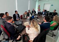 Várias pessoas sentadas reunidas em torno de uma mesa.