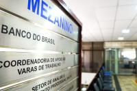 Placa metálica indicativa de locais. Há letras tanto na cor preta,  quanto na tonalidade azul.