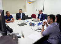 Quatro homens e uma mulher sentados em uma mesa conversando amigavelmente