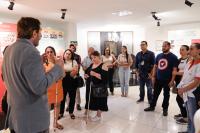 Homem de terno cinza fala para várias pessoas ques estão a sua frente. Há duas mulheres com bengalas. 