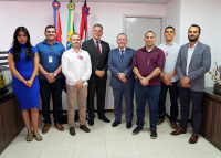Sete homens e uma mulher em pé, em frente as bandeiras de Alagoas, Brasil e TRT19