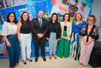 Há seis mulheres e um homem branco de terno posando para uma foto.