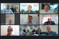 Foto de uma reunião híbrida com imagens de participantes no local do evento e demais participantes on-lina