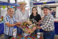 Três homens de camisa de xadrez e uma mulher de blusa preta segurando um balaio com produtos da feira agroecológica