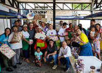 Há um grupo de pessoas posando para fotos. Uns estão de pé e outros agachados. Algumas dessa pessoas estão com presentes nas mãos.a
