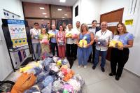 Várias pessoas reunidas para uma foto. Elas estão segurando sacolas com donativos para doação.