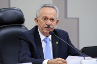 Homem idoso de cabelo grisalho, usando terno preto, camisa branca e gravata azul claro.
